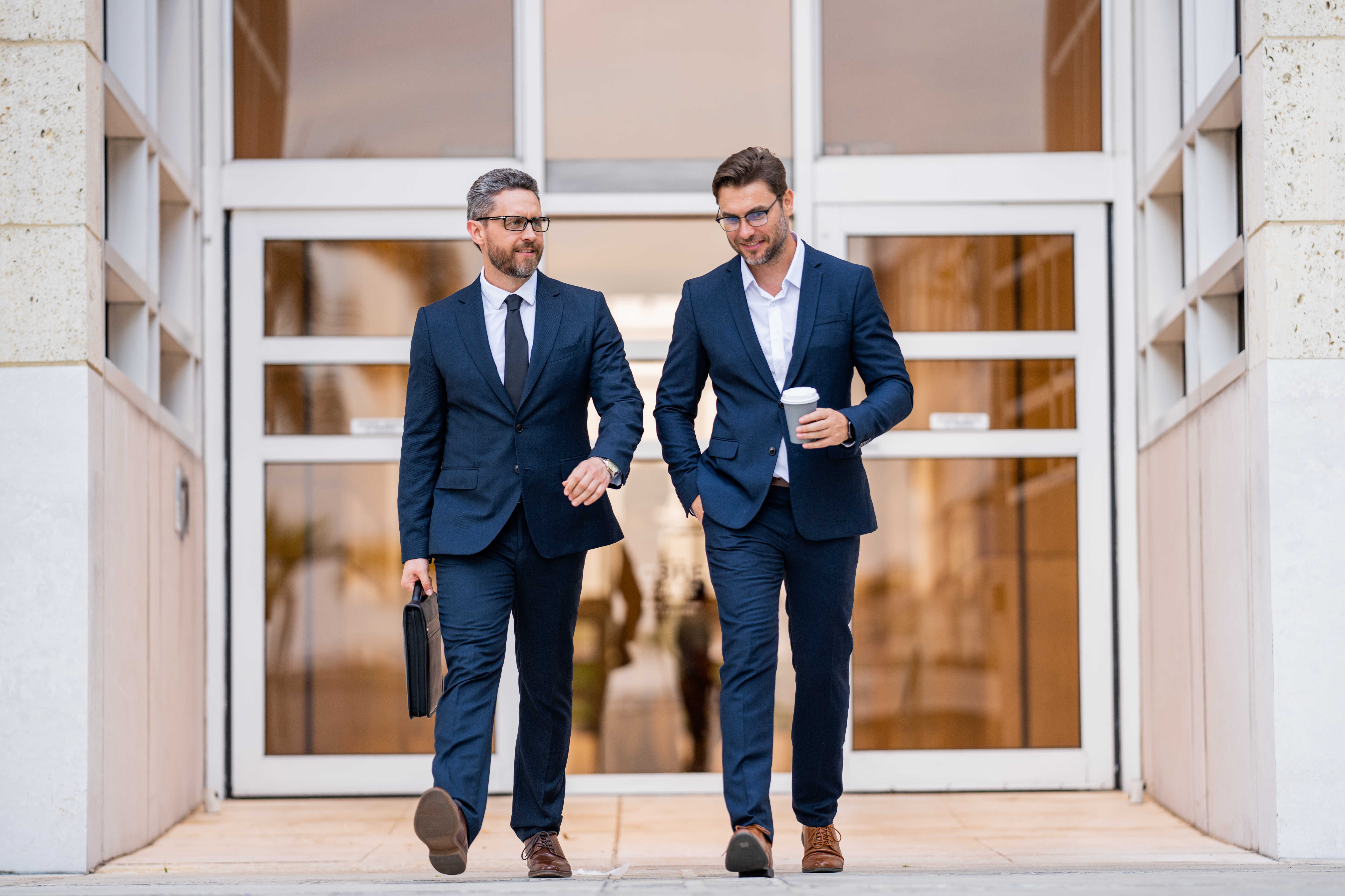 Two businessmen walking and talking at office building